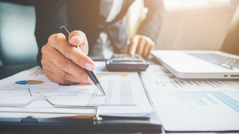 Personne analysant un tableau d'amortissement imprimé sur une feuille - Exact Online Immobilisations